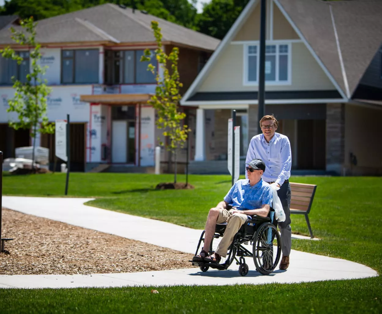 Image of someone pushing another person in a wheelchair at a park